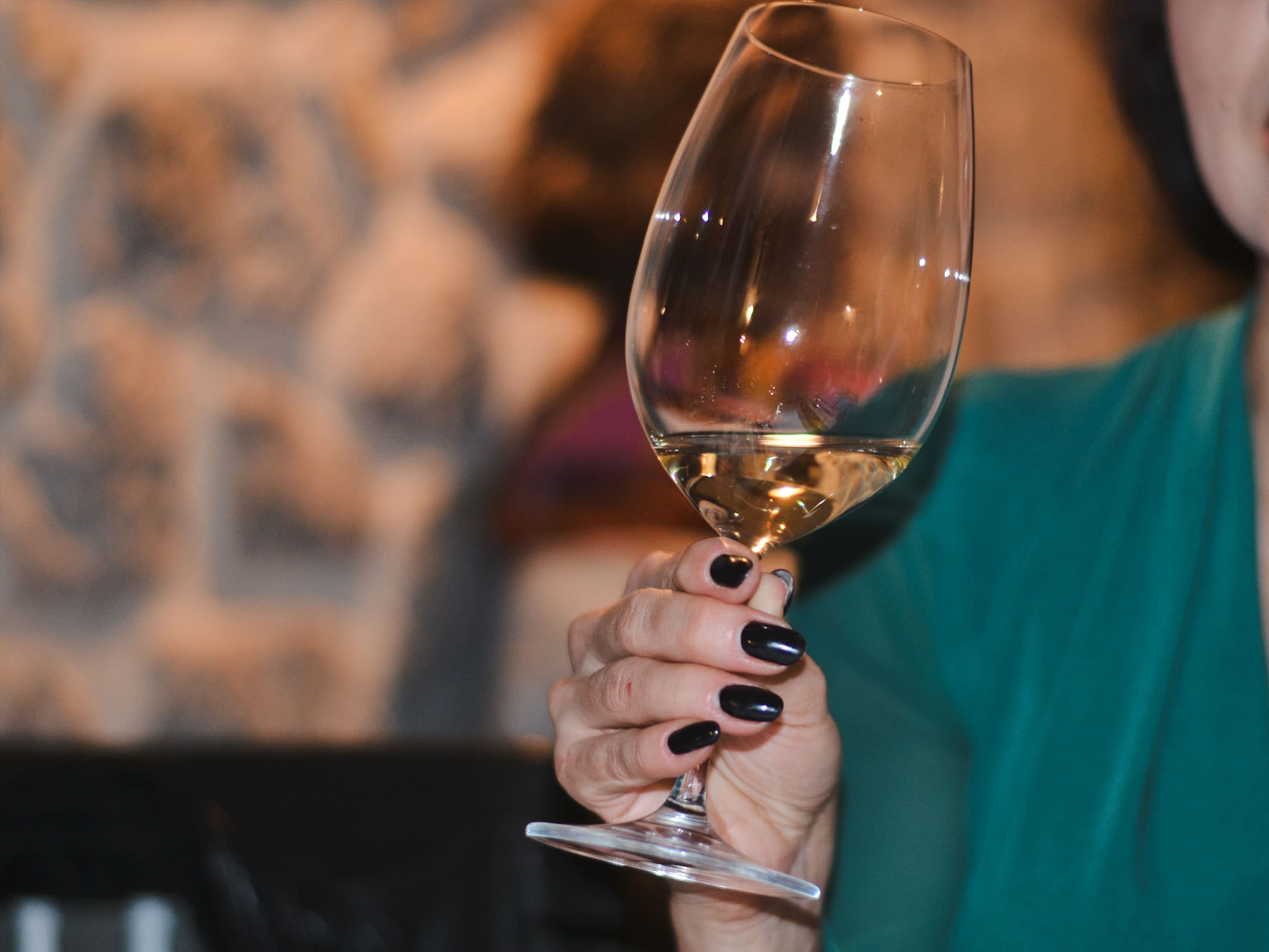 A guest of Conte restaurant holding a glass of white wine