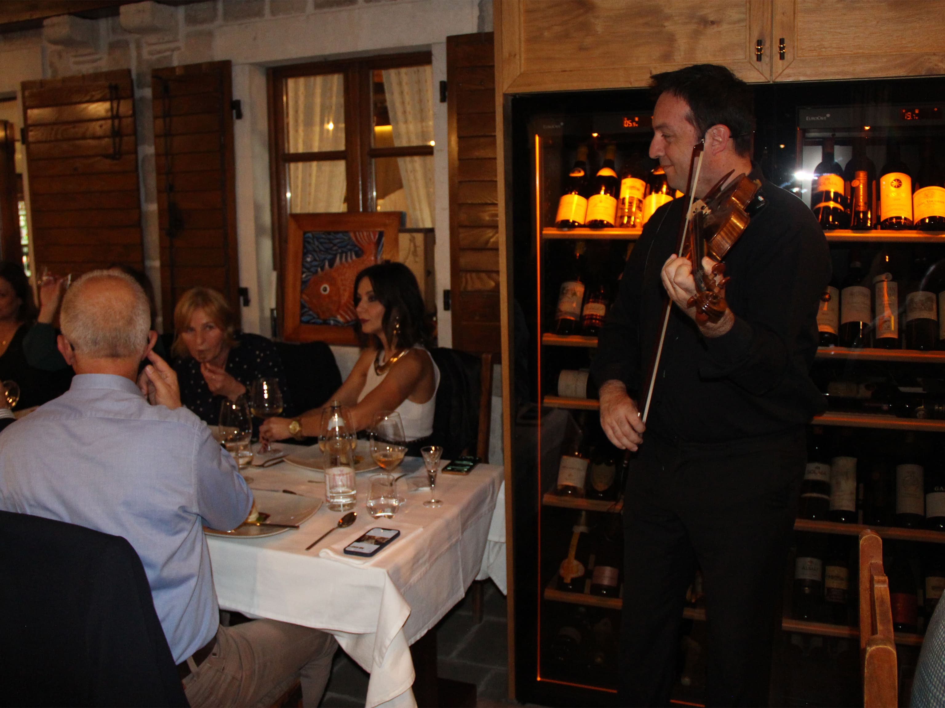 A violinist playing next to guests of Conte restaurant